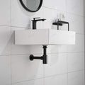 Table top basin bottle trap in matt black brass, cylindrical design with wall flange close-up