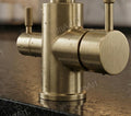 Close-up of dual lever controls on antique brass sink tap filter, smooth operation for hot, cold and filtered water
