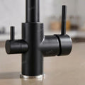 Close-up of dual lever controls on matte black kitchen dual lever mixer taps, brass deck mounted sink tap