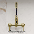 Wall mounted kitchen mixer tap in brushed gold, side angle showing 360° swivel spout and pull out spray head