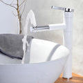 InArt hot and cold basin mixer tap installed on wash basin in bathroom interior, white and gold waterfall spout