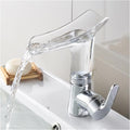 Transparent glass waterfall spout detail on brass basin mixer, steady cascade flow for wash basin
