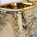Close-up of soft close toilet seat cover on square wall hung commode, glossy white ceramic with gold leaf design