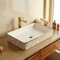 Close-up of golden floral polished rim on ceramic table top wash basin, premium bathroom sanitaryware detail