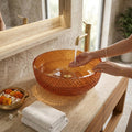 Close-up of amber glass wash basin design with light reflections, smooth round rim detail